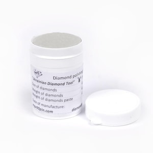 以下が含まれることがあります： 白い円筒形の容器で、蓋が外れて横に置かれています。「Ukrainian Diamond Tool」と書かれたラベルには、ダイヤモンドとペーストのサイズと重量に関する情報が記載されています。背景は白です。