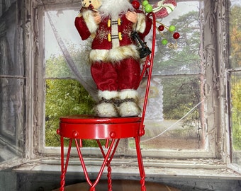 Santa Claus standing on a miniature Soda fountain chair