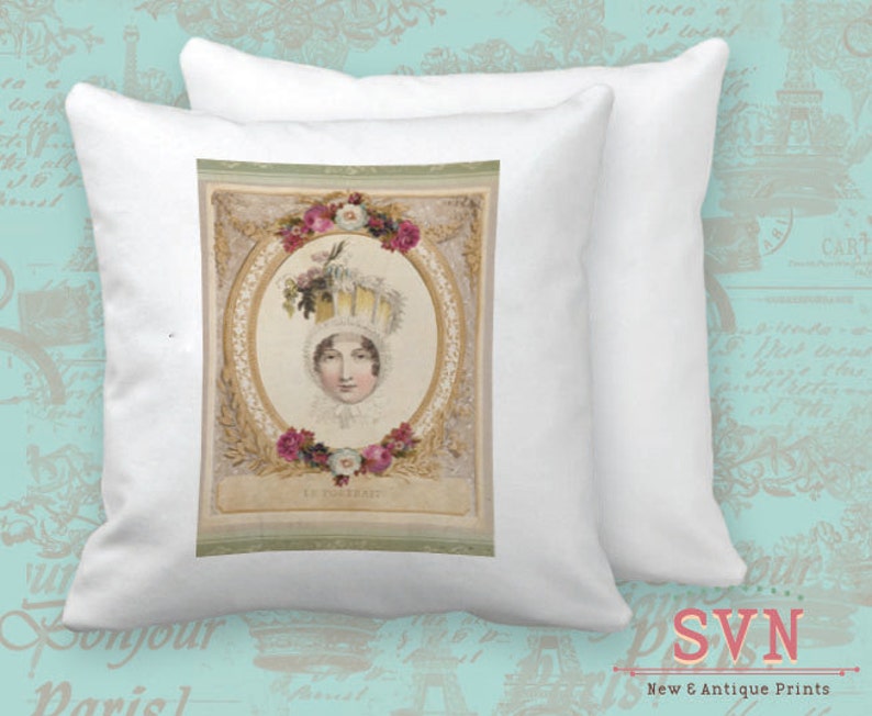 May include: A white pillow with a vintage illustration of a woman wearing a large, ornate hat with flowers. The illustration is framed with a gold and white border and has a light green background. The text "Le Portrait" is printed below the image.
