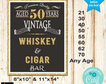 May include: A black and gold sign with the text "AGED 50 YEARS VINTAGE WHISKEY & CIGAR BAR." The sign is framed with a gold glitter border and includes size options of 20.3cm x 25.4cm and 27.9cm x 35.6cm.