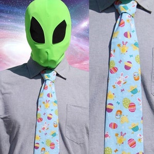 May include: A light blue tie with a pattern of colorful Easter eggs, chicks, and bunnies.