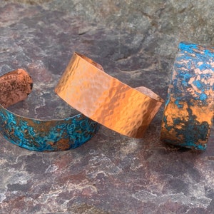 May include: Three copper bracelets with a hammered texture. Two of the bracelets have a blue-green patina finish.