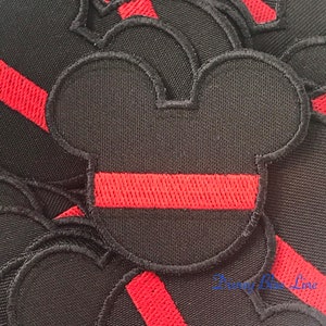 May include: A set of black felt Mickey Mouse head patches with a red embroidered stripe across the middle.
