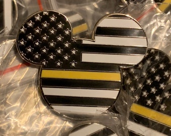 May include: A black and white Mickey Mouse pin with a thin yellow stripe across the middle. The Mickey Mouse head is shaped like the American flag with white stars on a black background. The bottom half of the Mickey Mouse head is shaped like a black and white striped flag with a thin yellow stripe across the middle.