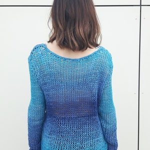 May include: A blue and turquoise knitted jumper with a loose fit and long sleeves.