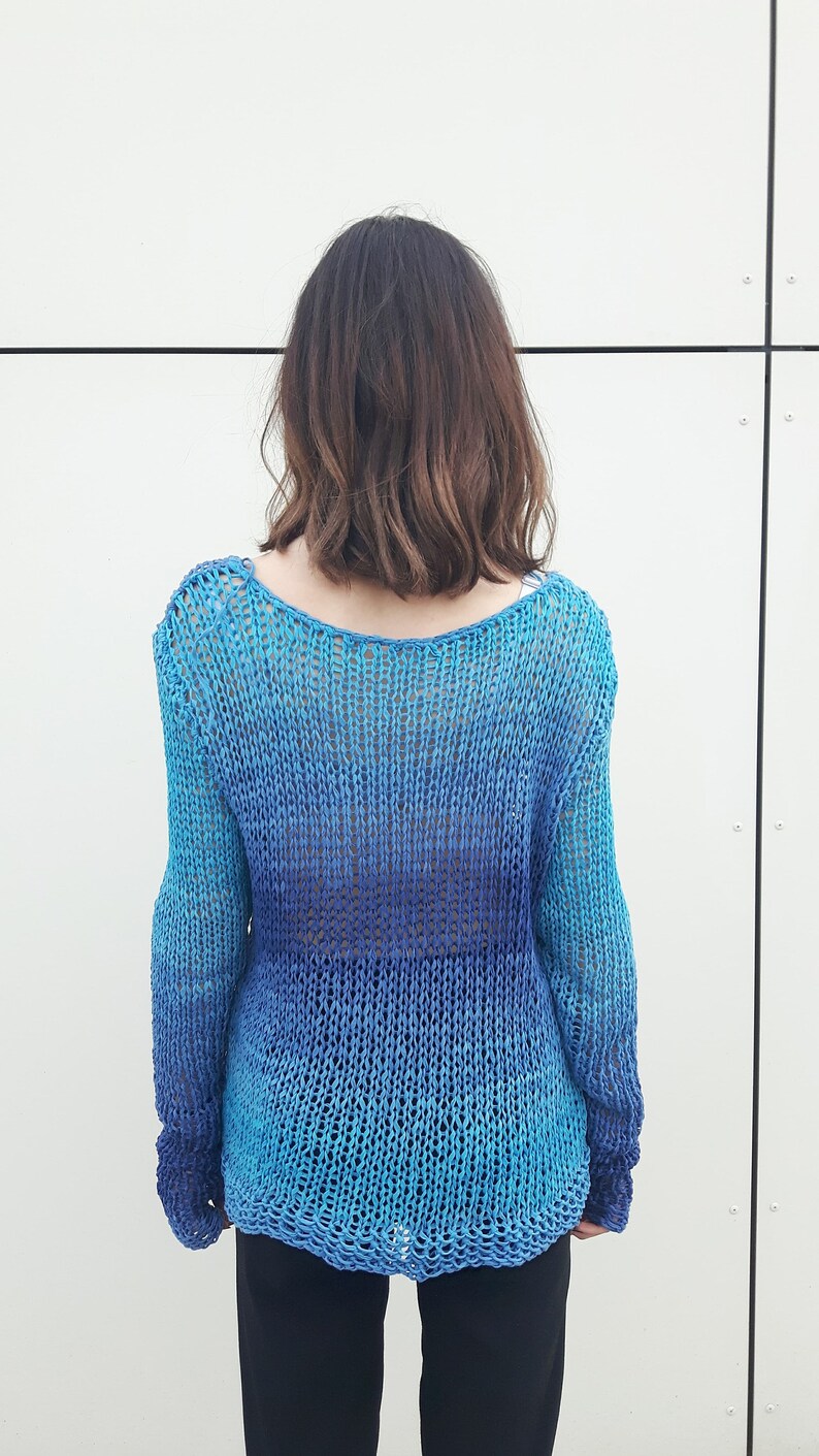 May include: A blue and turquoise knitted jumper with a loose fit and long sleeves.