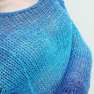 May include: A blue and turquoise crochet top with a loose fit and long sleeves. The top is made of a lightweight, breathable fabric and has a relaxed, casual style.
