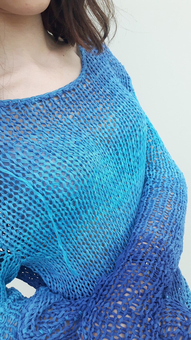 May include: A blue and turquoise crochet top with a loose fit and long sleeves. The top is made of a lightweight, breathable fabric and has a relaxed, casual style.