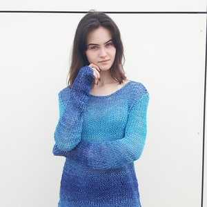 May include: A blue and turquoise ombre knit sweater with long sleeves and a loose fit.