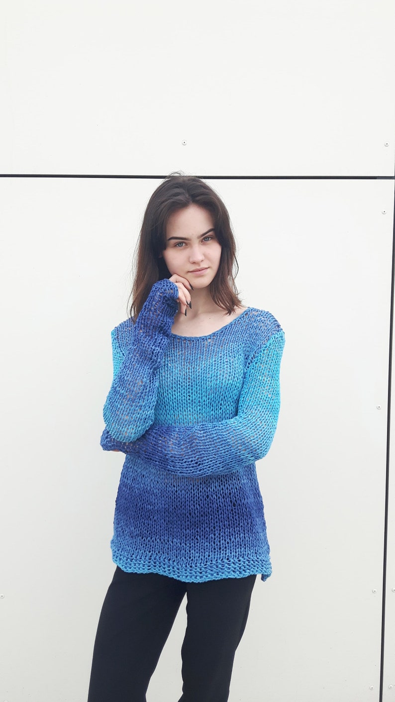 May include: A blue and turquoise ombre knit sweater with long sleeves and a loose fit.