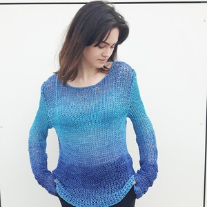 May include: A blue and turquoise ombre knit sweater with a loose fit and long sleeves.