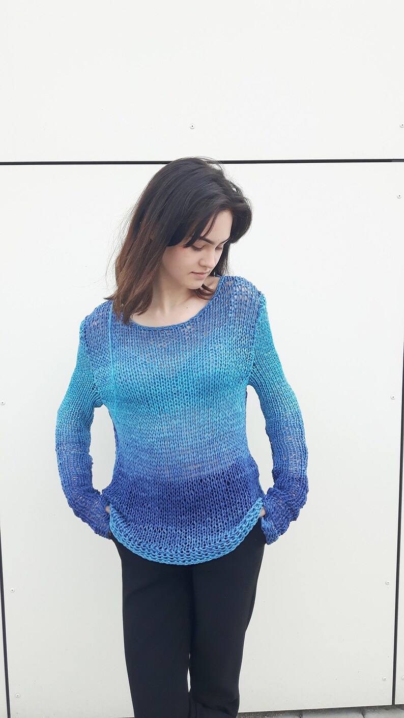 May include: A blue and turquoise ombre knit sweater with a loose fit and long sleeves.