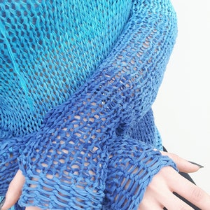 May include: A blue and turquoise knitted jumper with a loose fit and a large open stitch pattern.