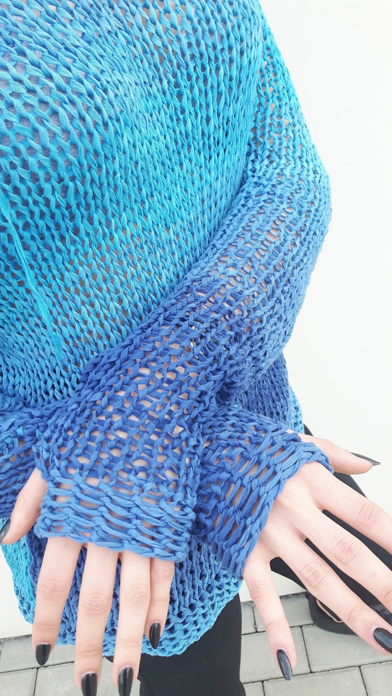May include: A blue and turquoise knitted jumper with a loose fit and a large open stitch pattern.