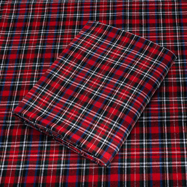 May include: Red and black plaid fabric with a white and blue plaid fabric folded on top.