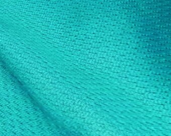 May include: Close-up of a turquoise fabric with a textured woven pattern.