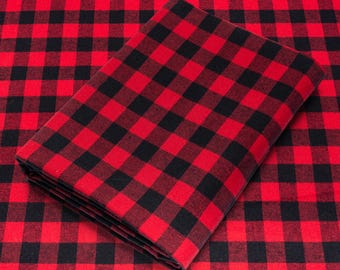 May include: Red and black checkered fabric. The fabric is folded in half and the edges are visible.