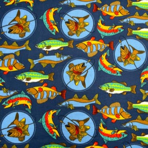 May include: A blue fabric with a repeating pattern of colorful fish. The fish are in various positions, some are swimming, some are jumping, and some are caught on a fishing line. The background is a dark blue color.