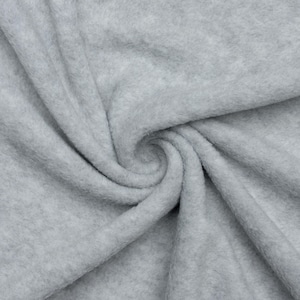 May include: Close-up of a soft, gray fleece fabric. The fabric is folded and twisted, showing its texture and drape.