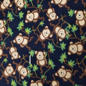 May include: A navy blue fabric with a repeating pattern of brown monkeys swinging from green vines. The monkeys have white faces and are smiling.