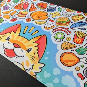 May include: A colorful mousepad with a cartoon cat and a variety of food illustrations, including pizza, burgers, fries, and sushi. The text "YUM CHIPS" is visible on a bag of chips.