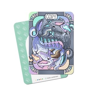 Op de afbeelding: Een fantasy art kaart met twee draken, een grijze en een lichtblauwe, verweven op een grijze achtergrond. De kaart heeft het woord "COPY" bovenaan en is omgeven door pastelkleuren. De achterkant van de kaart is lichtgroen met pootafdrukken.