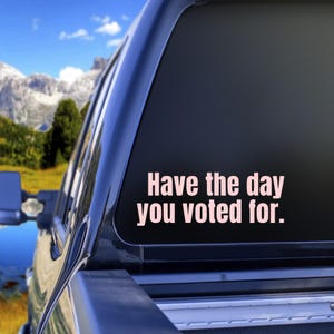 May include: A black truck with a pink vinyl sticker on the back window that says "Have the day you voted for."