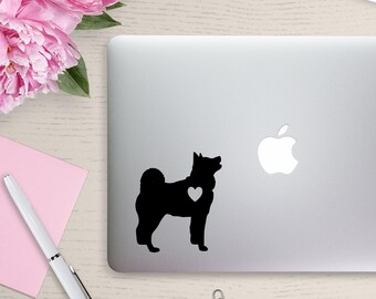 May include: Black silhouette of a dog with a white heart on its chest on a silver laptop.