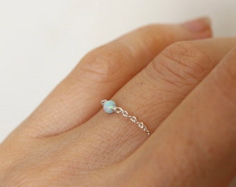 May include: A delicate silver chain ring with a single white opal gemstone.