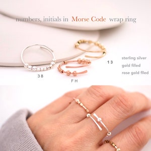 May include: Three silver, gold, and rose gold rings with beads in a Morse code pattern. The rings are labelled with the numbers 38, FH, and 13. The text "sterling silver", "gold filled", and "rose gold filled" is also visible.