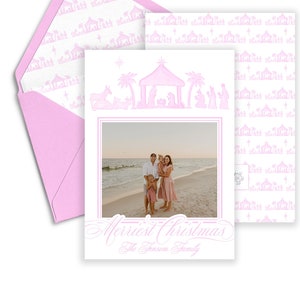 May include: A pink Christmas card with a family photo on the front. The card features a nativity scene design in pink, with the words "Merriest Christmas" and "The Fraser Family" in a script font. An envelope with a matching pattern is included.