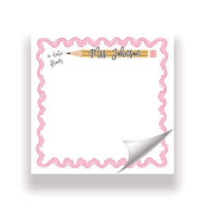 Può includere: Un blocco note quadrato con un bordo rosa ondulato e l'angolo in basso a destra ripiegato. La parte superiore presenta un disegno di una matita gialla con il testo 'a note from' e 'Mrs. Johnson' in corsivo nero su sfondo bianco.