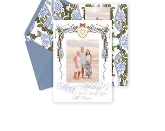 Op de afbeelding: Een kerstkaart met een blauw en wit bloemenpatroon. De kaart heeft een foto van een gezin van drie personen die op een strand staan. De tekst op de kaart luidt "Prettige Kerstdagen Van onze familie aan de uwe De Owens".