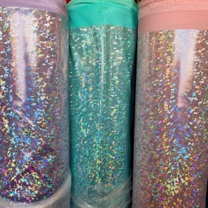 May include: Three rolls of iridescent fabric in purple, teal, and pink. The fabric has a glittery, holographic finish.