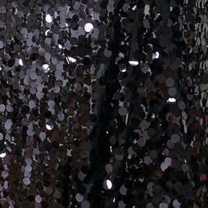 May include: Black fabric with a pattern of small, round sequins.