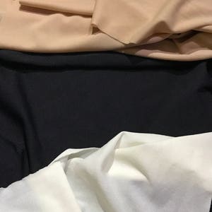 May include: Three fabric swatches in different colors: beige, black, and white. The fabric is smooth and has a slight sheen.