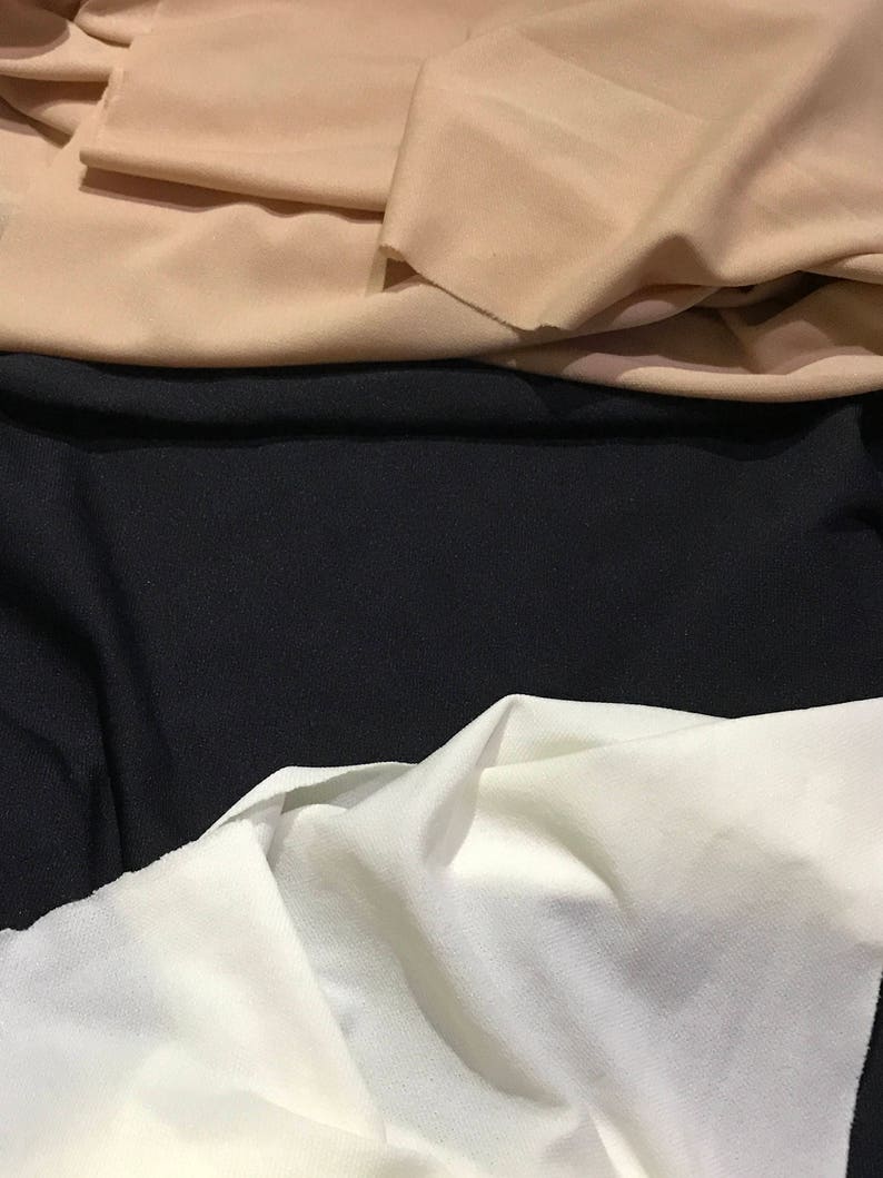 May include: Three fabric swatches in different colors: beige, black, and white. The fabric is smooth and has a slight sheen.