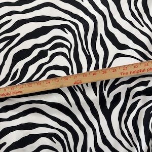 May include: Black and white zebra print fabric. The fabric is measured with a ruler that reads "The helpful place."
