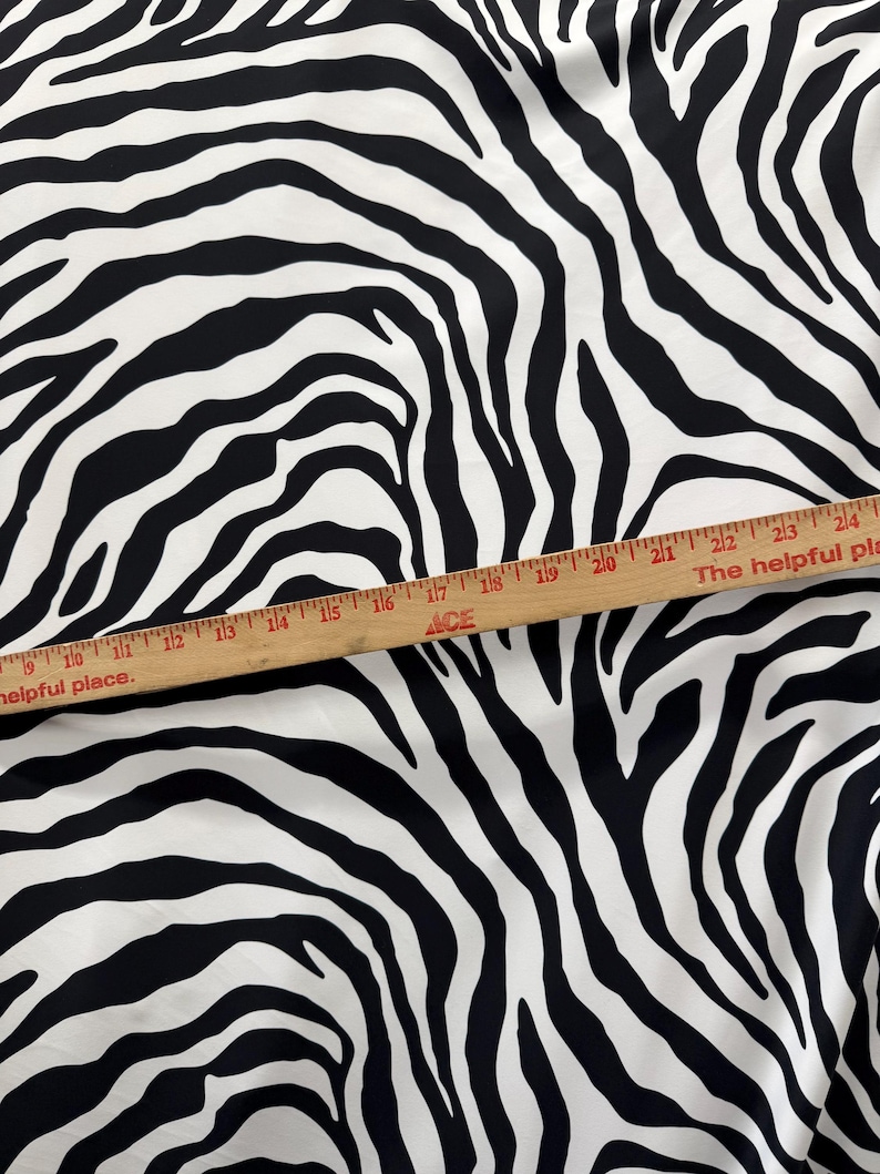 May include: Black and white zebra print fabric. The fabric is measured with a ruler that reads "The helpful place."