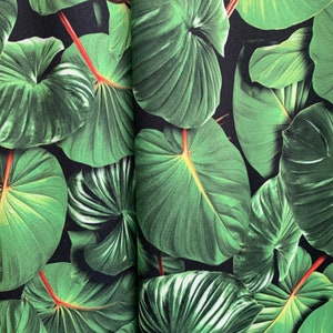 May include: A close-up of a fabric with a repeating pattern of large, green leaves on a black background.