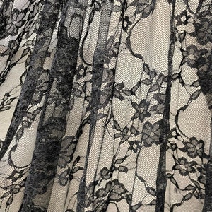 May include: Black lace fabric with a delicate floral pattern. The lace is sheer and has a soft, flowing texture.
