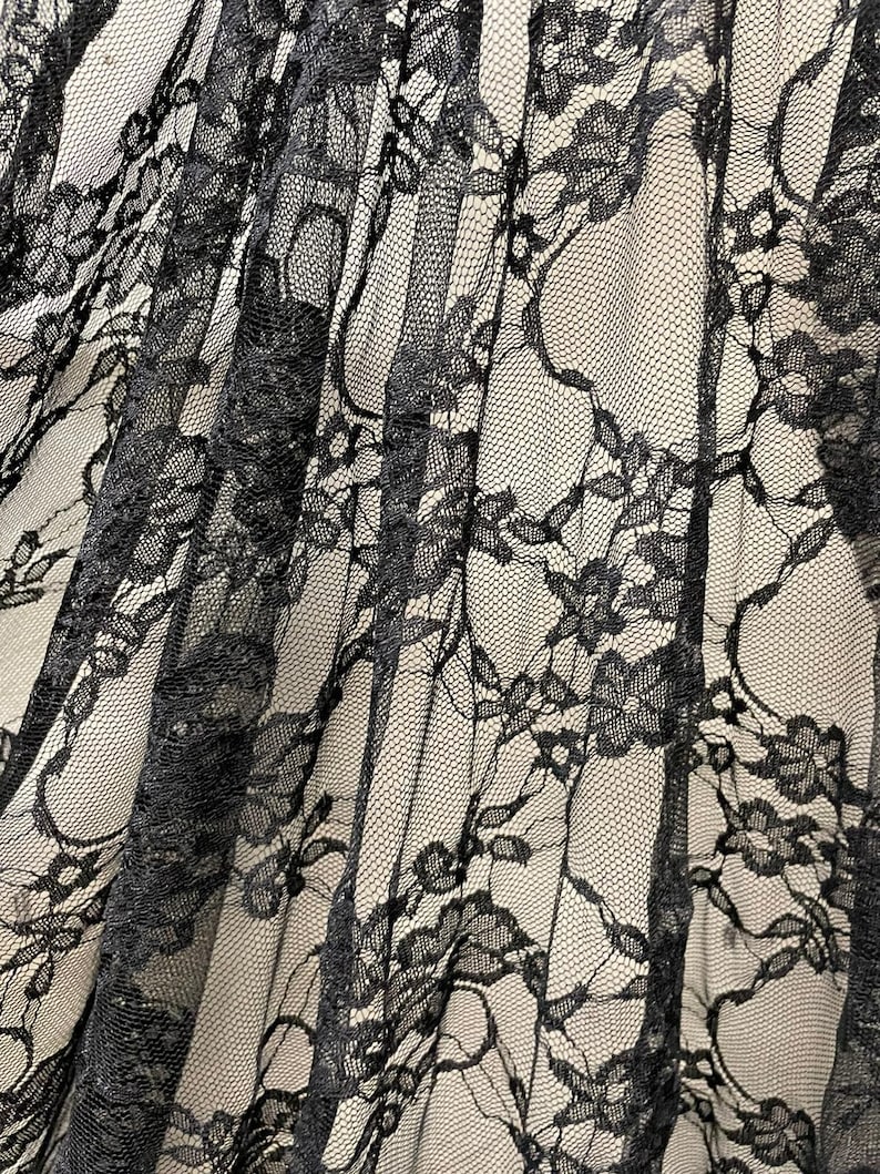 May include: Black lace fabric with a delicate floral pattern. The lace is sheer and has a soft, flowing texture.