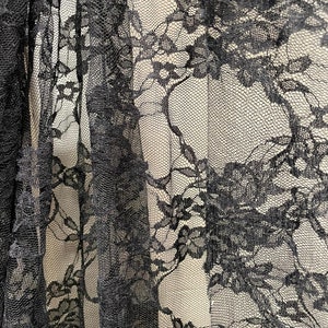 May include: Black lace fabric with a floral pattern. The lace is delicate and intricate, with a fine mesh background.