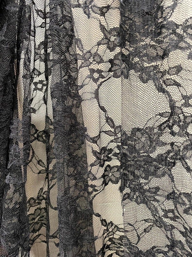 May include: Black lace fabric with a floral pattern. The lace is delicate and intricate, with a fine mesh background.