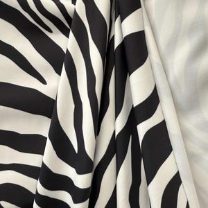 May include: Black and white zebra print fabric. The fabric is folded and shows the pattern from different angles.
