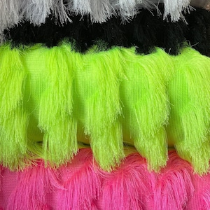 May include: Four different colours of fringe trim fabric. The colours are white, black, neon green, and hot pink.