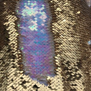 May include: Gold fabric with iridescent sequins in a mermaid scale pattern. The sequins are arranged in a diagonal pattern, with the iridescent sequins forming a large shape in the centre.
