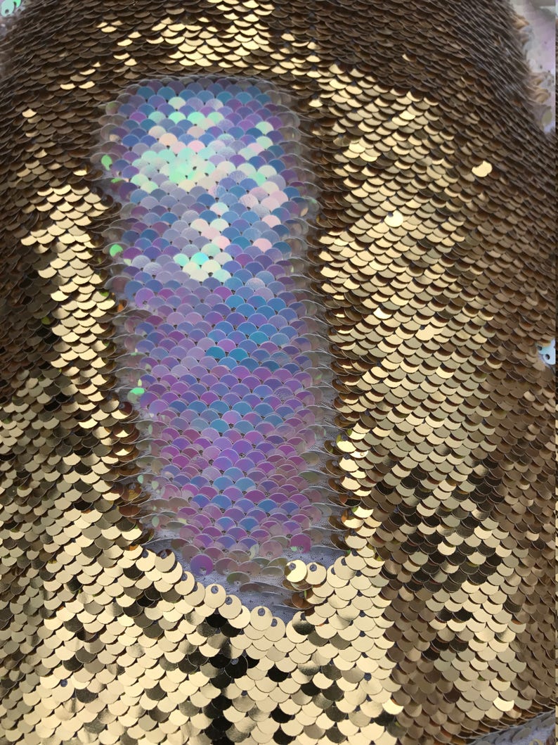 May include: Gold fabric with iridescent sequins in a mermaid scale pattern. The sequins are arranged in a diagonal pattern, with the iridescent sequins forming a large shape in the centre.