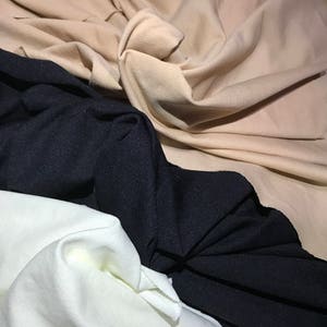 May include: Three fabric swatches in different colors: beige, black, and white. The fabric is soft and has a slight texture.
