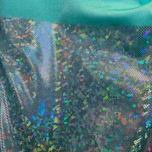 May include: Teal iridescent fabric with a small, repeating pattern of iridescent dots. The fabric has a slight sheen and is semi-transparent.
